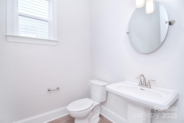 bathroom with toilet, baseboards, and a sink