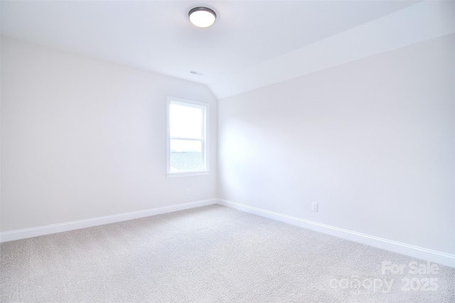 carpeted spare room with baseboards and vaulted ceiling