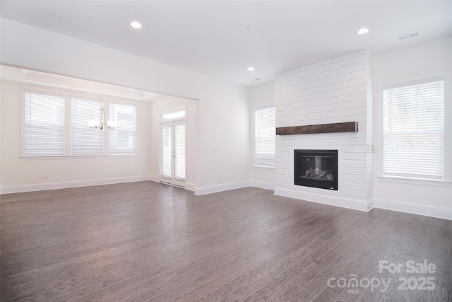 unfurnished living room with baseboards, visible vents, dark wood finished floors, and a fireplace