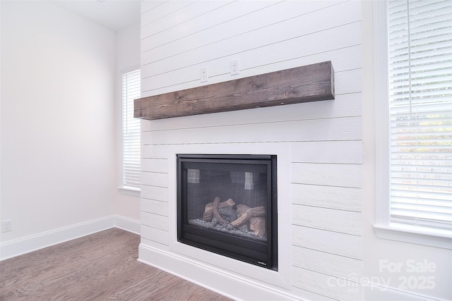 interior details featuring a glass covered fireplace, baseboards, and wood finished floors