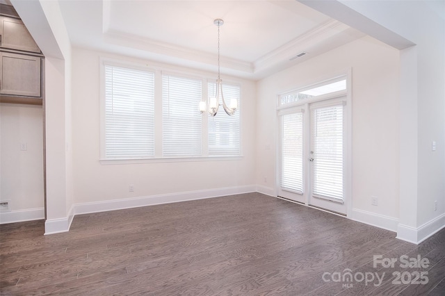 unfurnished dining area with dark wood-style floors, a raised ceiling, ornamental molding, and baseboards