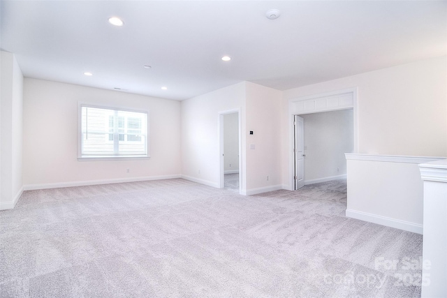 empty room with light carpet, baseboards, and recessed lighting