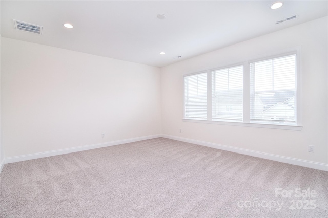 spare room with visible vents, light carpet, and baseboards