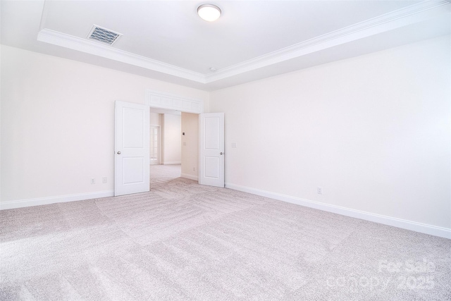 spare room with light carpet, baseboards, visible vents, ornamental molding, and a tray ceiling