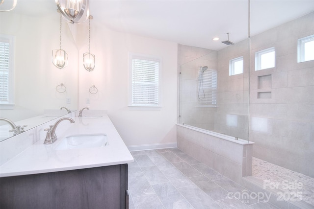 full bath featuring a walk in shower, double vanity, a sink, and baseboards