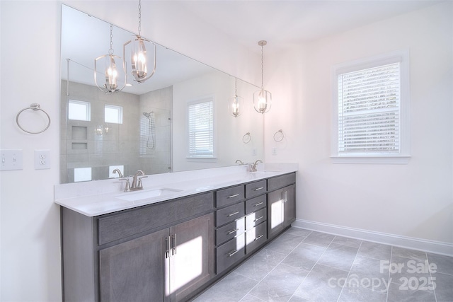 bathroom featuring double vanity, baseboards, tiled shower, a chandelier, and a sink