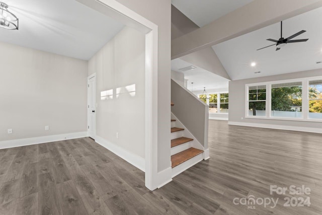 stairs featuring ceiling fan with notable chandelier, hardwood / wood-style floors, and vaulted ceiling with beams