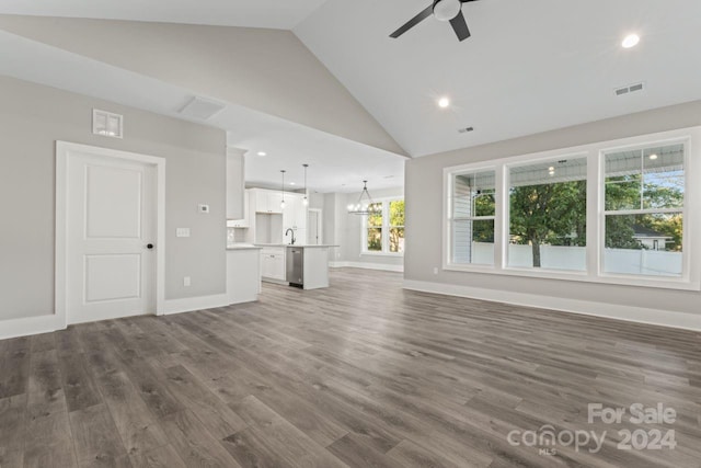 unfurnished living room with ceiling fan with notable chandelier, dark hardwood / wood-style flooring, high vaulted ceiling, and sink