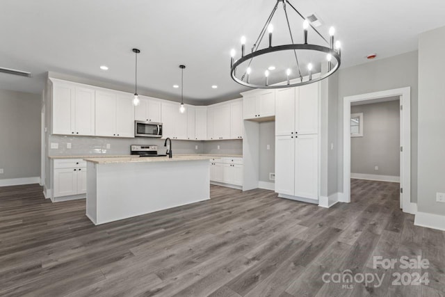 kitchen with an island with sink, pendant lighting, white cabinets, and stainless steel appliances