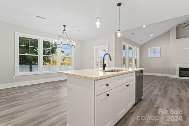 kitchen with white cabinetry, sink, light stone counters, decorative light fixtures, and a center island with sink