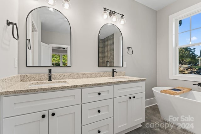 bathroom featuring tile patterned floors, a tub, plenty of natural light, and vanity