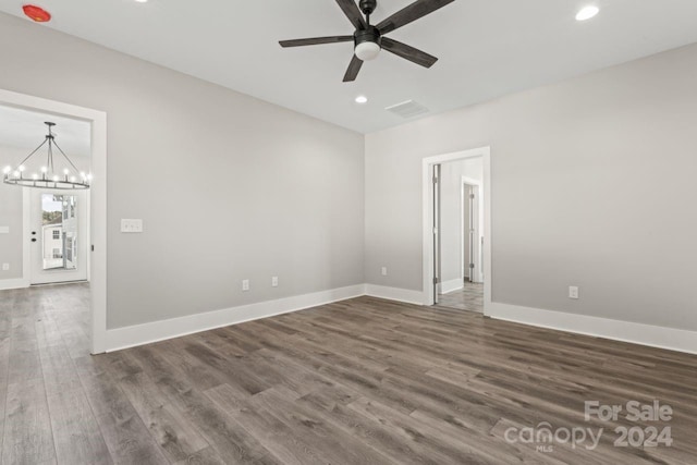 empty room with ceiling fan with notable chandelier and dark hardwood / wood-style floors