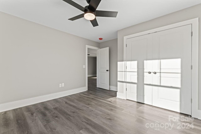 unfurnished bedroom featuring ceiling fan, a closet, and hardwood / wood-style flooring