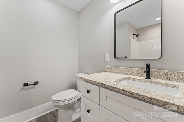 bathroom featuring a shower, hardwood / wood-style flooring, vanity, and toilet