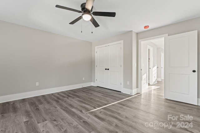 unfurnished bedroom featuring ceiling fan, a closet, and wood-type flooring