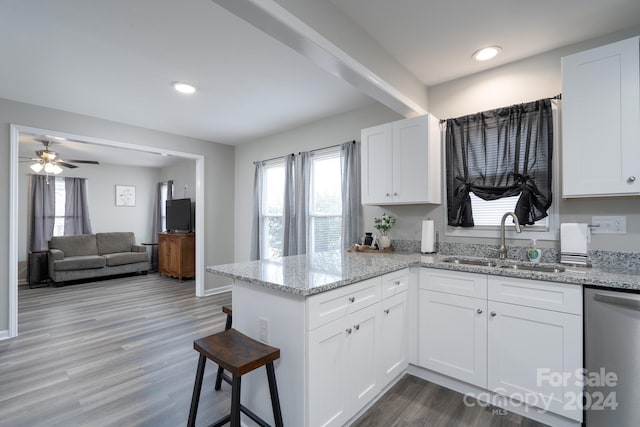 kitchen featuring dishwasher, sink, light stone counters, kitchen peninsula, and white cabinets