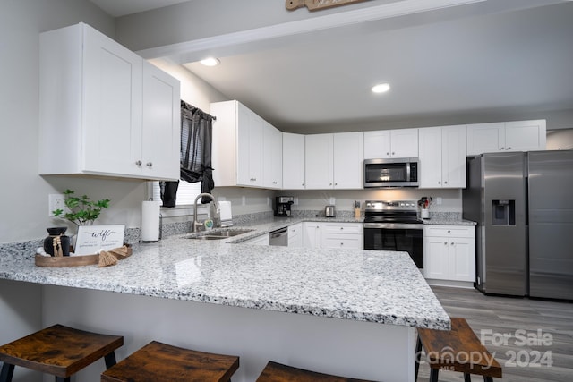 kitchen featuring sink, stainless steel appliances, a kitchen breakfast bar, kitchen peninsula, and white cabinets