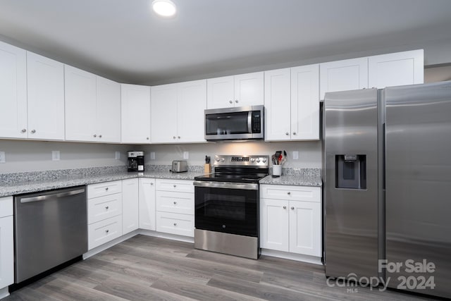 kitchen featuring white cabinets, light stone countertops, stainless steel appliances, and dark hardwood / wood-style floors