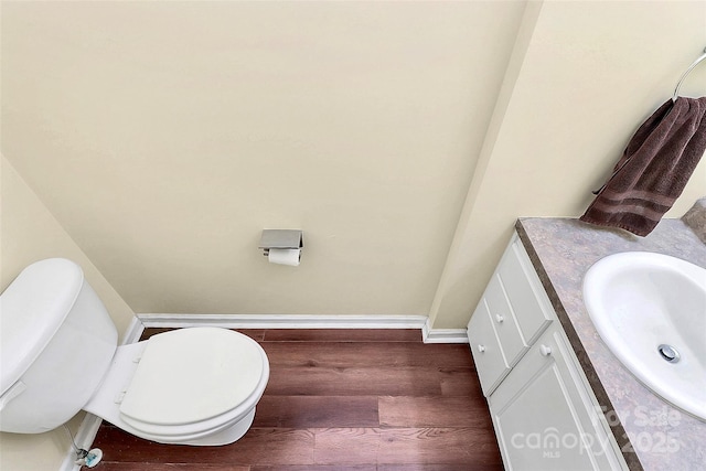 bathroom featuring toilet, vanity, and hardwood / wood-style floors