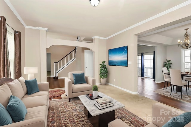 living area with arched walkways, baseboards, a notable chandelier, stairway, and ornamental molding