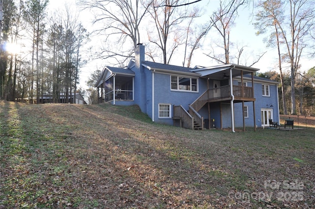 back of house featuring a lawn and a sunroom