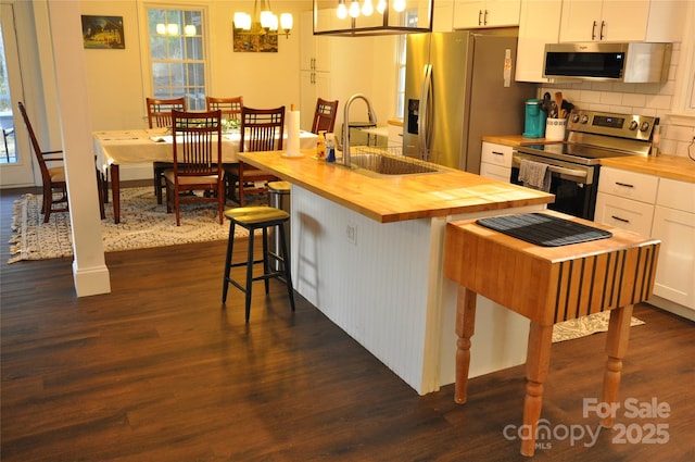 kitchen with sink, a kitchen breakfast bar, decorative light fixtures, white cabinets, and appliances with stainless steel finishes