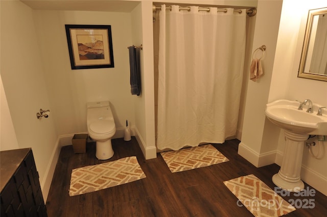 bathroom with hardwood / wood-style flooring, toilet, and walk in shower