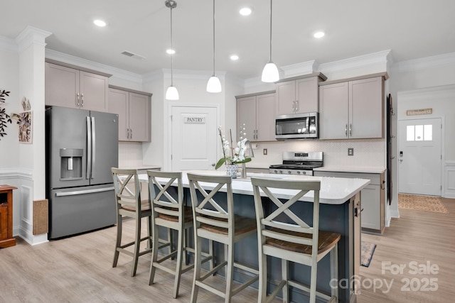 kitchen with a kitchen bar, appliances with stainless steel finishes, backsplash, gray cabinetry, and pendant lighting