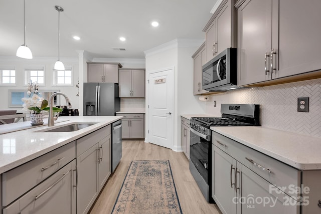 kitchen featuring gray cabinetry, tasteful backsplash, crown molding, pendant lighting, and appliances with stainless steel finishes