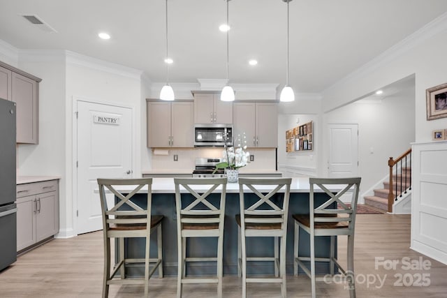 kitchen featuring gray cabinets, a center island with sink, decorative light fixtures, and appliances with stainless steel finishes