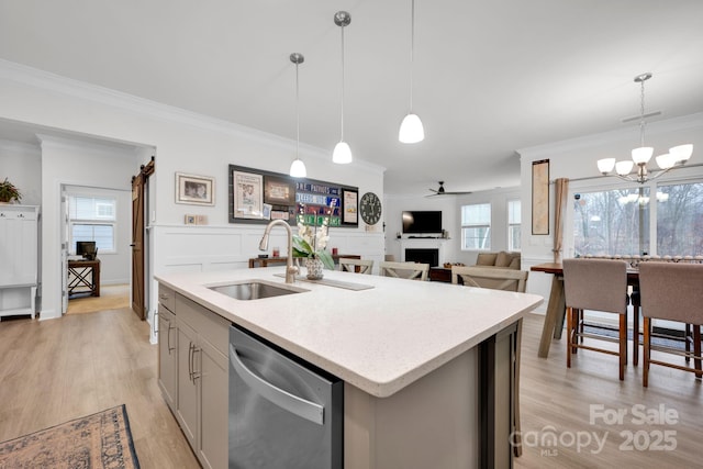 kitchen with a kitchen island with sink, dishwasher, hanging light fixtures, and sink