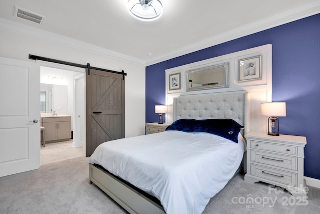 carpeted bedroom featuring a barn door, ensuite bathroom, and crown molding