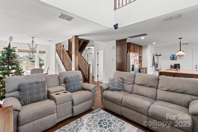 living room with dark wood-type flooring, sink, a textured ceiling, and a chandelier