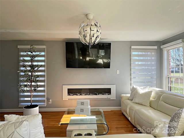 living room with a wealth of natural light, a notable chandelier, and hardwood / wood-style flooring