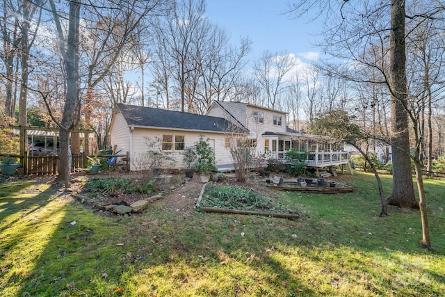 back of house with a wooden deck, a sunroom, and a yard