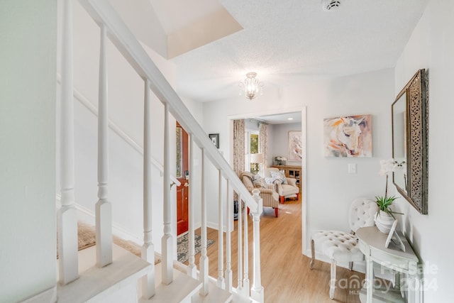 entrance foyer featuring a textured ceiling, light hardwood / wood-style flooring, and a notable chandelier