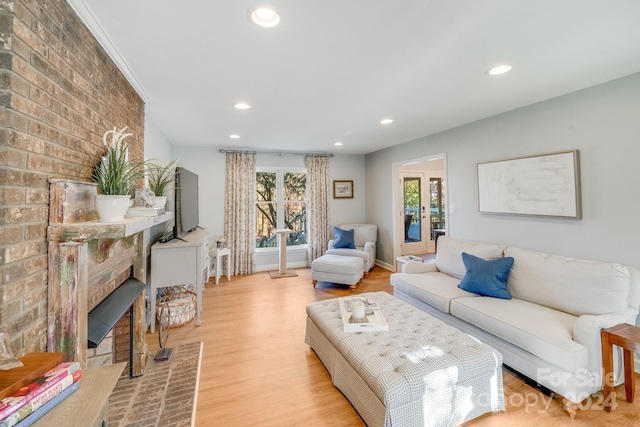 living room featuring light wood-type flooring and a brick fireplace