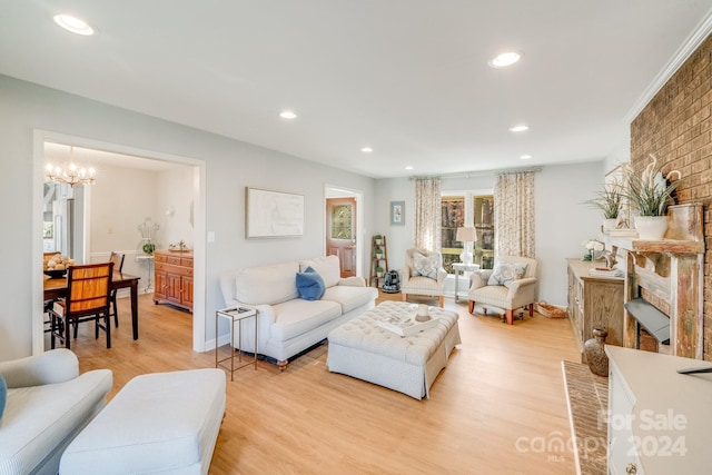 living room with a chandelier, light wood-type flooring, and a brick fireplace