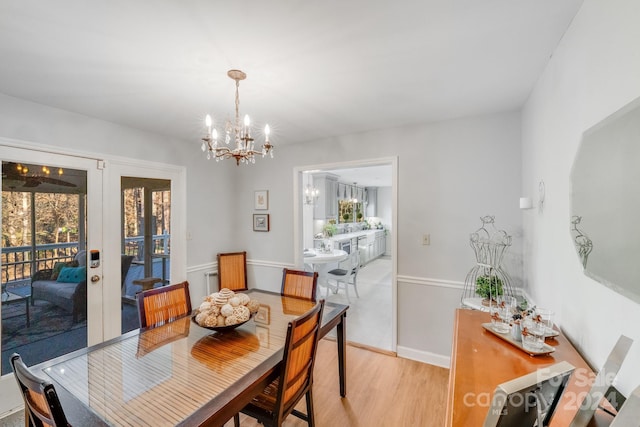 dining space featuring light hardwood / wood-style flooring, french doors, and a notable chandelier