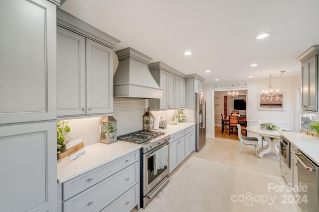 kitchen with tasteful backsplash, a notable chandelier, gray cabinets, appliances with stainless steel finishes, and custom exhaust hood