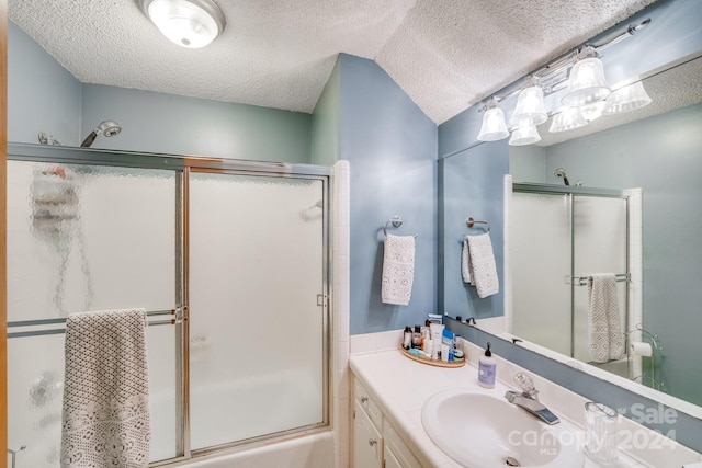 bathroom with vanity, enclosed tub / shower combo, and a textured ceiling