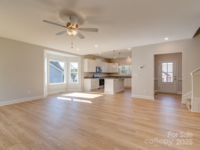 unfurnished living room with ceiling fan, a healthy amount of sunlight, and light hardwood / wood-style floors