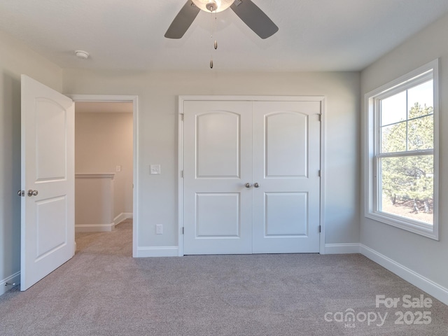 unfurnished bedroom featuring light carpet, a closet, and ceiling fan