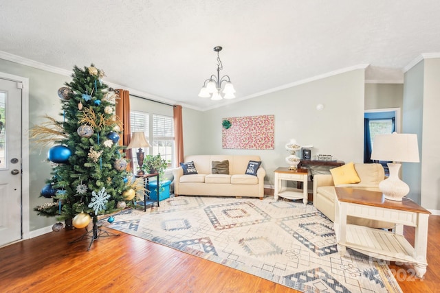 living room with a textured ceiling, hardwood / wood-style floors, a notable chandelier, and ornamental molding