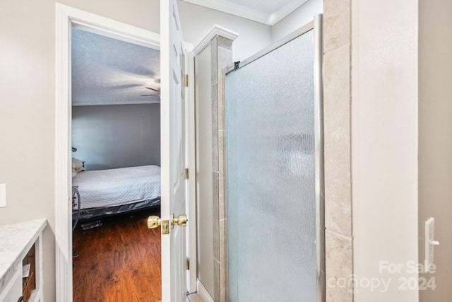 bathroom featuring a textured ceiling, crown molding, wood-type flooring, and an enclosed shower