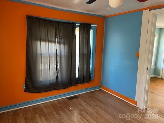 unfurnished room with wood-type flooring, ceiling fan, and ornamental molding