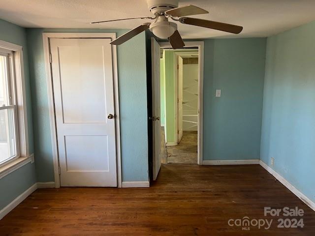 unfurnished bedroom with multiple windows, dark hardwood / wood-style flooring, a closet, and ceiling fan