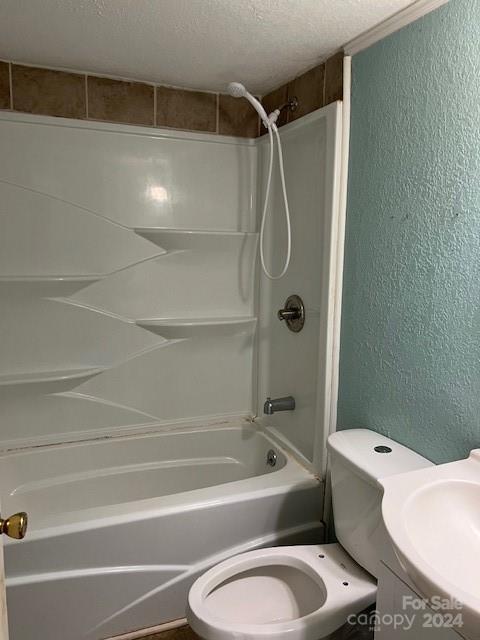 full bathroom featuring vanity, washtub / shower combination, a textured ceiling, and toilet