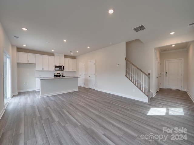 unfurnished living room featuring light hardwood / wood-style flooring and ornamental molding