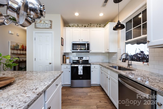 kitchen featuring sink, hanging light fixtures, backsplash, white cabinets, and appliances with stainless steel finishes